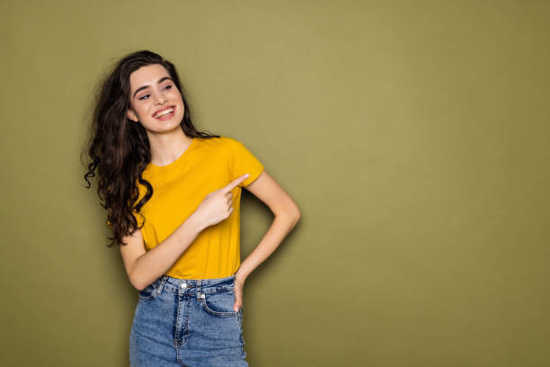 istock Full body young woman point index finger aside indicate on workspace area copy space mock up isolated on khaki background 1475463988