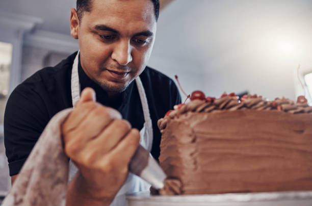 istock Piping, kitchen and man baking a cake with chocolate or pastry chef preparing a recipe at a bakery. Food, dessert and professional baker making a sweet meal and adds cream or icing 1475464159