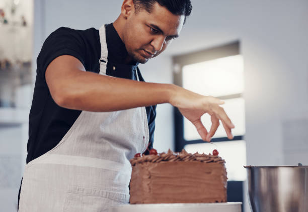 istock Kitchen, baking and man decorating cake with chocolate sprinkles and frosting with focus and skill. Sweets, small business and baker decorating dessert for birthday event and pastry chef in bakery. 1475464203