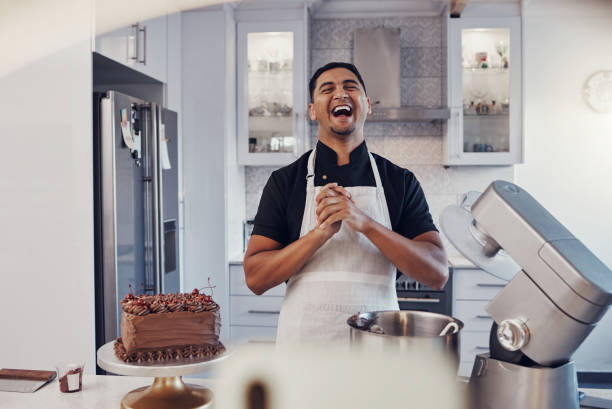 istock Man, baker and laughing in kitchen on vlog, live streaming and recording a cake tutorial on social media. Happy chef, digital content creator and food influencer filming a funny virtual cooking class 1475464570