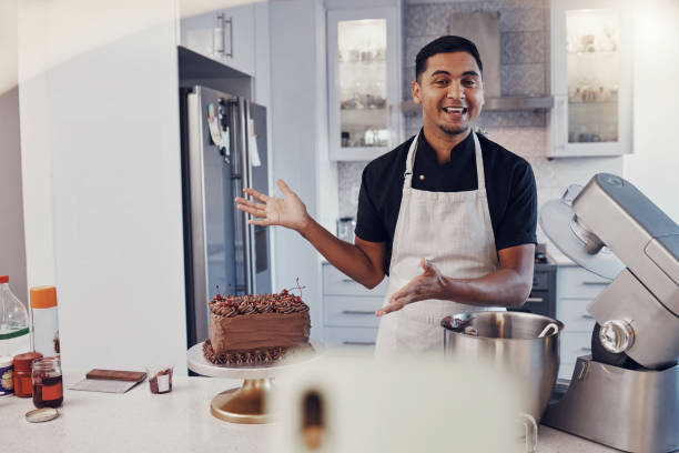 istock Man, chef and talking in kitchen on vlog, live streaming and recording a cake dessert tutorial on social media. Happy baker, digital content creator or food influencer filming a virtual cooking class 1475464579