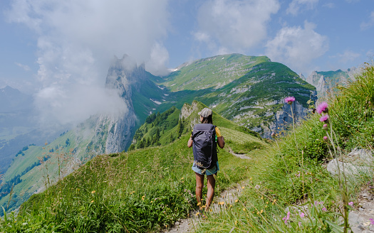 Asian women hiking in the Swiss Alps mountains during summer vacation with a backpack and hiking boots. woman walking on the Saxer Lucke path a popular hiking trail in Switzerland
