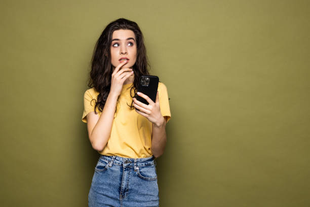 istock Young woman hold in hand use mobile cell phone typing read message isolated on khaki background. People lifestyle concept 1475464632