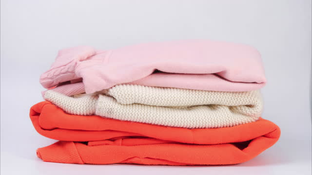 Stop motion of piles of colorful clothes on white background. Clothes for donation or shopping. Household laundry.