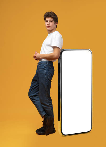 istock Handsome young man standing leaned on huge smartphone over yellow background 1475468286