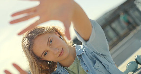 Hand frame, beauty and portrait of woman in city for fashion, trendy cosmetics and stylish clothes in urban street. Relax, summer and face of happy girl smile with hands for wellness, style and model