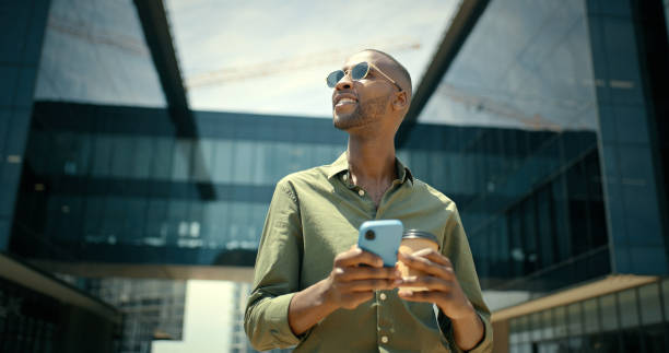 istock Phone, coffee and black man typing in city, texting or web scrolling in low angle. Thinking, sunglasses and happy business male with 5g mobile smartphone for networking, social media or messaging. 1475472151