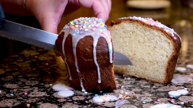 A woman's hand cuts an Orthodox Easter cake in honor of Easter on the kitchen table