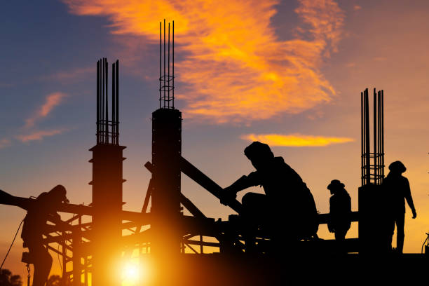 istock Silhouette of Engineer and worker checking project at building site background, construction site at sunset in evening time 1475473756