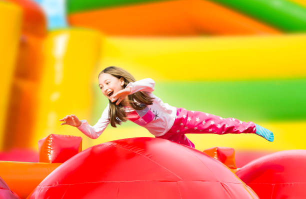 chica feliz saltando en el patio de recreo inflar el castillo - inflatable child playground leisure games fotografías e imágenes de stock