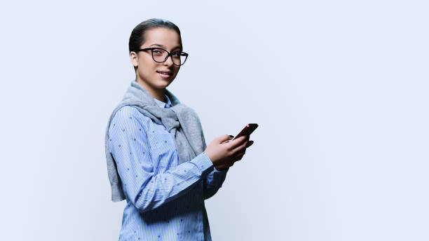 istock Young female with smartphone, looking at camera on white background 1475475640