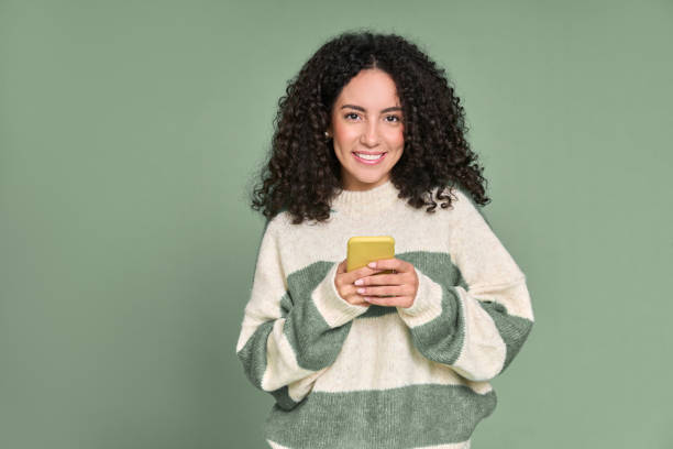 istock Young happy latin woman using mobile phone isolated on green background. 1475478654
