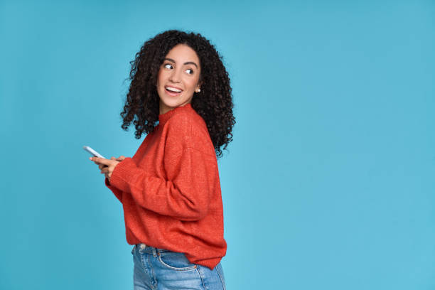 istock Young smiling latin woman using mobile phone isolated on blue background. 1475478671