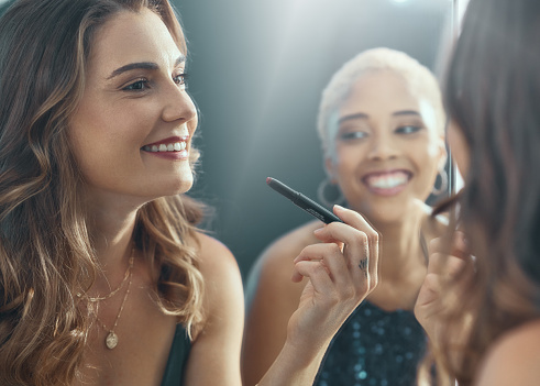Makeup, smile and women getting ready for a party, social celebration and lipstick for an event. Happy, mirror reflection and friends with cosmetics for a girls night, new year and disco together