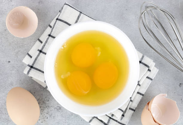 istock Cooking baking ingredients eggs, whisk and kitchen textiles on gray concrete background. Pie or cake recipe. Top view. 1475481515