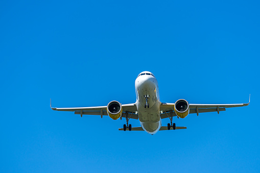 Low Angle View Of Landing Airplane Against Blue Sky