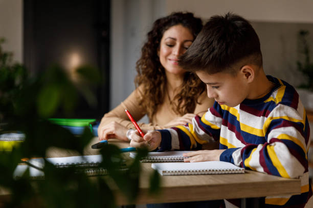 istock Boy writing homework and studying with assistance from his mother 1475484114
