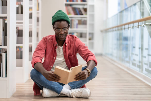 istock Focused African American guy preparing materials for upcoming lecture reading book in university 1475484511