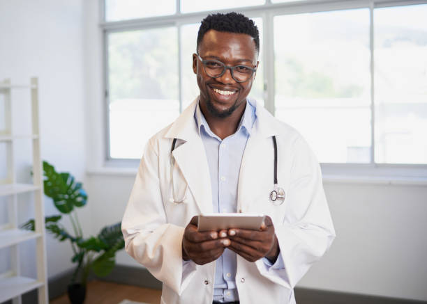 Portrait of a young Black doctor using digital tablet in bright office stock photo