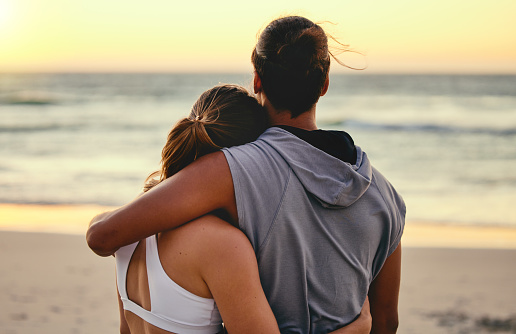 Hug, fitness and back of couple at the beach for sunset training, exercise and workout with a view. Peace, gratitude and runner man and woman hugging with affection after cardio at the ocean