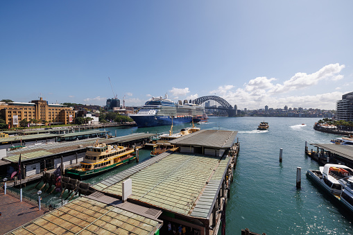 Sydney, Australia - March 15th, 2023: Sydney Harbor with Opera House, Harbor Bridge, Sydney Ferries, and Cruise ship “Celebrity Eclipse ” moored. Sunny day.