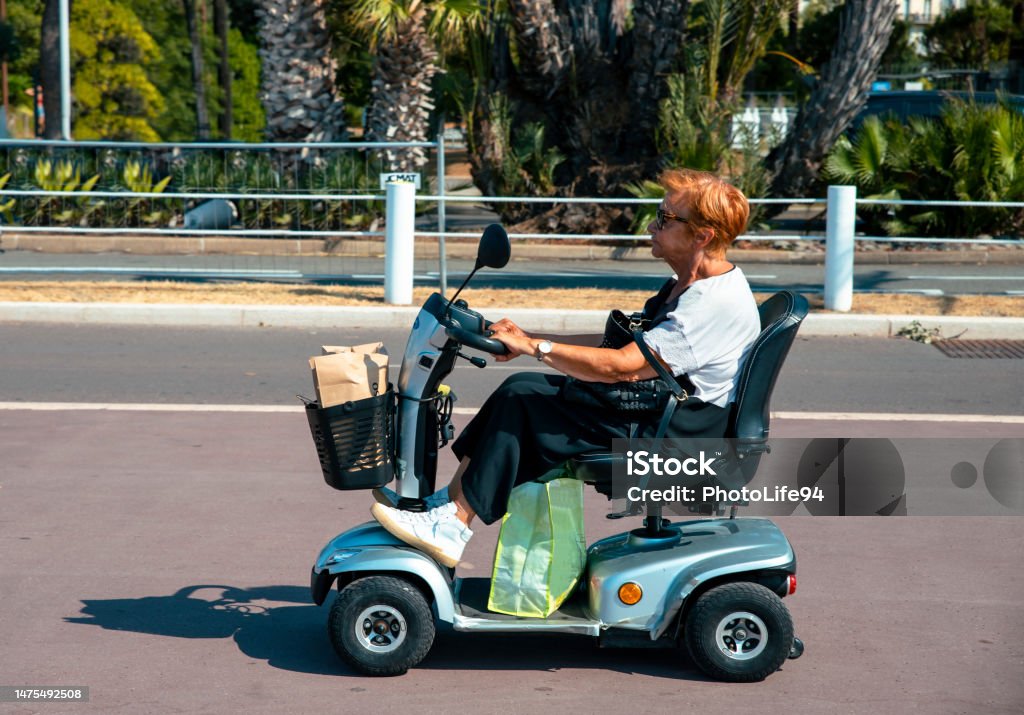 Still on the move! Senior Woman driving small electric tricycle vehicle on the street. Copy space Mobility Scooter Stock Photo