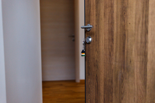 Close-up of open door and door handle with a key and a keychain shaped house