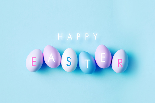 Happy Easter message over colorful Easter eggs and blue background. Horizontal composition with copy space. Easter concept.