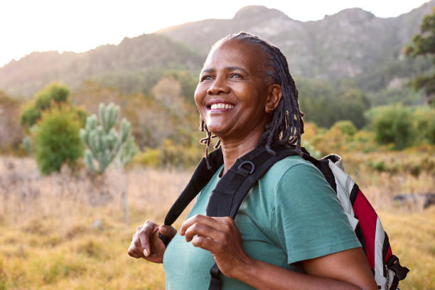 ritratto di donna anziana attiva con lo zaino che va per l'escursione in campagna - hiking senior adult exercising outdoors foto e immagini stock