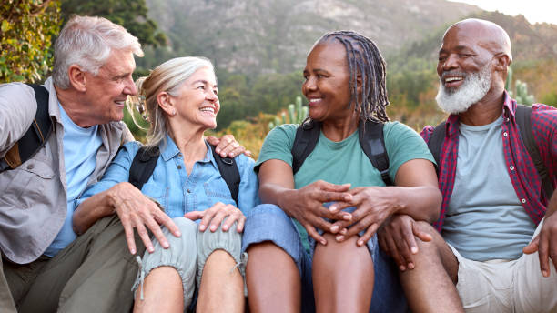 istock Active Senior Friends Sitting Taking A Break Hiking Through Countryside Together 1475495228