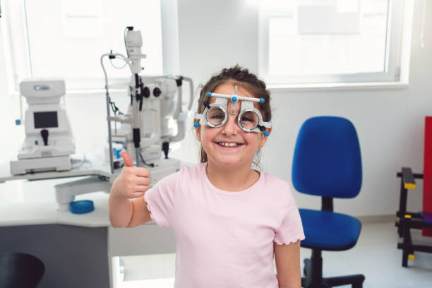 istock Girl showing thumb up while wearing trial frame used for eyesight tests, at the ophthalmology clinic 1475496870