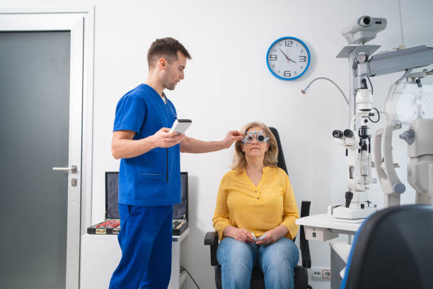 Male ophthalmologist, examining senior female patient eyesight, while using trial frame and different lenses