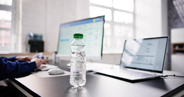 istock Water Bottle On Desk And Man In Background 1475501645