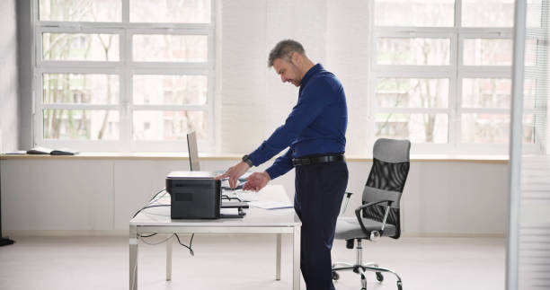 istock Irritated Businessman Looking At Paper Stuck In Printer 1475503130
