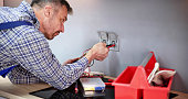 Male Electrician Checking Voltage Of Socket With Multimeter