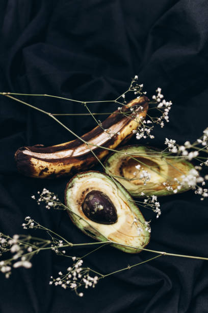 Rotten avocado and banana on a back background, food photography, Earth day concept
