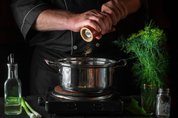 istock The chef adds pepper to the saucepan while making dumplings. Working environment on vintage kitchen table in restaurant. 1475512695