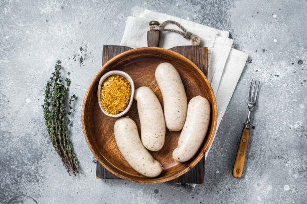 Bavarian white sausage in wooden plate with mustard. Gray background. Top view Bavarian white sausage in wooden plate with mustard. Gray background. Top view. weisswurst photos stock pictures, royalty-free photos & images