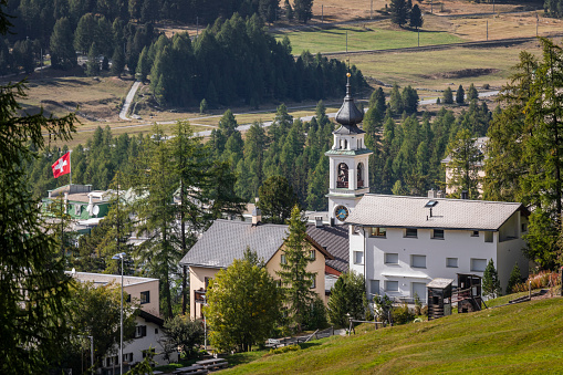 Swiss flag waving over Pontresina alpine village, Engadine Valley, Graubunden, Swiss Alps