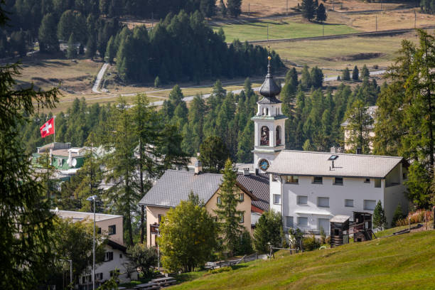 bandeira suíça acenando sobre a aldeia alpina de pontresina, vale da engadine, graubunden, alpes suíços - engadine switzerland village church - fotografias e filmes do acervo