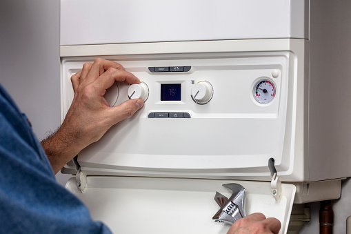 Plumber technician servicing or repairing home central heating system boiler