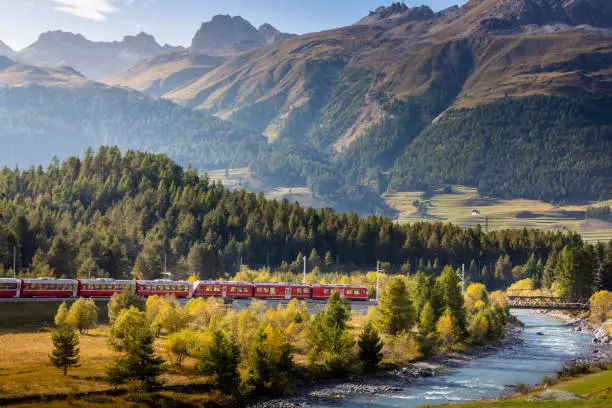 Red Train and river with alpine Landscape near St. Moritz, Engadine Valley, Graubunden, Swiss Alps