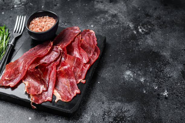 pastrami a fette turche (kayseri pastirma), carne di manzo essiccata con spezie su tavola di marmo. sfondo nero. vista dall'alto. spazio di copia - bresaola foto e immagini stock