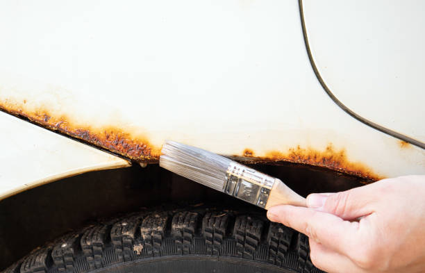 vista ravvicinata della mano della persona applicare il liquido di arresto della ruggine dell'auto per uso domestico sulle parti arrugginite del veicolo. - rust covered foto e immagini stock