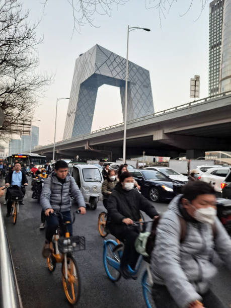 la gente anda en bicicleta a lo largo de la carretera guagnhua en el 3er anillo este de la ciudad después del trabajo por la noche, con el fondo de la torre central de televisión de china. - beijing traffic land vehicle city street fotografías e imágenes de stock