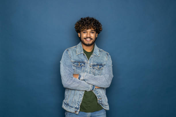 istock Young indian elegant man standing over isolated blue background happy face smiling with crossed arms looking at the camera. Positive person. 1475524388