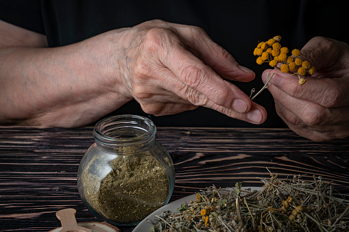 Dried medicinal herb, antiparasitic collection of tansy, wormwood and cloves (troychatka). The herbalist pours the crushed collection into a jar.