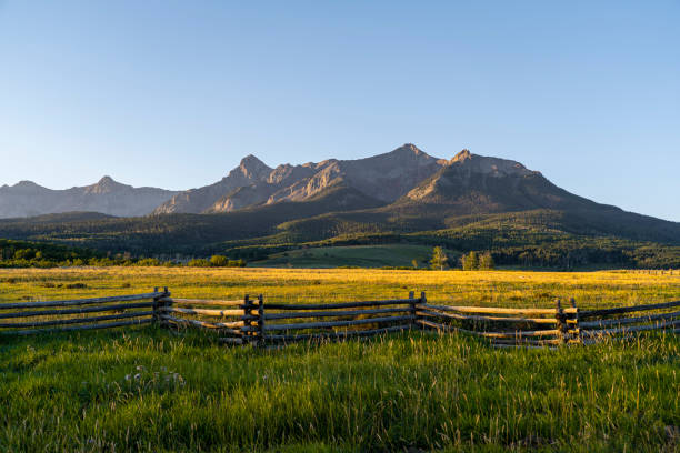 Early morning sunrise at the foot of the mountains in Colorado An early morning sunrise in the San Juan Mountains in southwestern Colorado. Sunlight falls on the landscape below, creating long shadows and contrast in the scene. Not a cloud in the sky. ridgway stock pictures, royalty-free photos & images