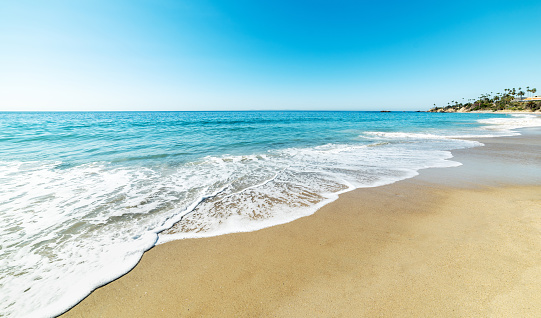 Ocean waves breaking on white sand beach with turquoise emerald coloured water