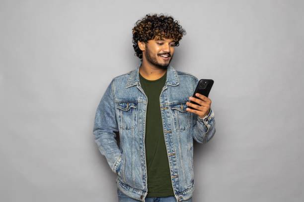 istock Excited indian business man using cell mobile phone isolated on gray background. 1475526905